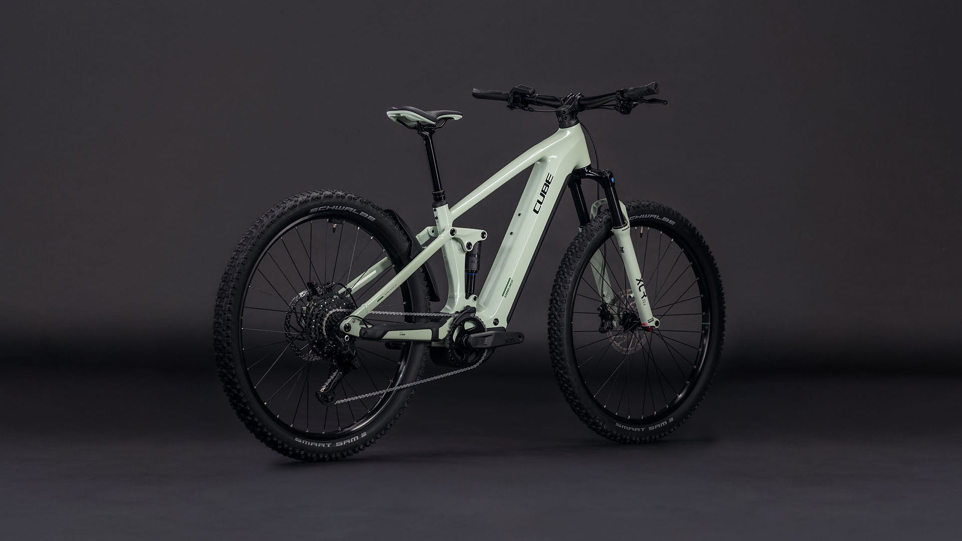 Das CUBE Stereo Hybrid ONE22 Pro 800 stonegrey'n'black 2026 E-Mountainbike, ausgestattet mit dicken, robusten Reifen, einem stabilen Rahmen und Bosch CX Antrieb, wird auf einem dunklen Hintergrund mit Seiten- und Heckwinkeln gezeigt.