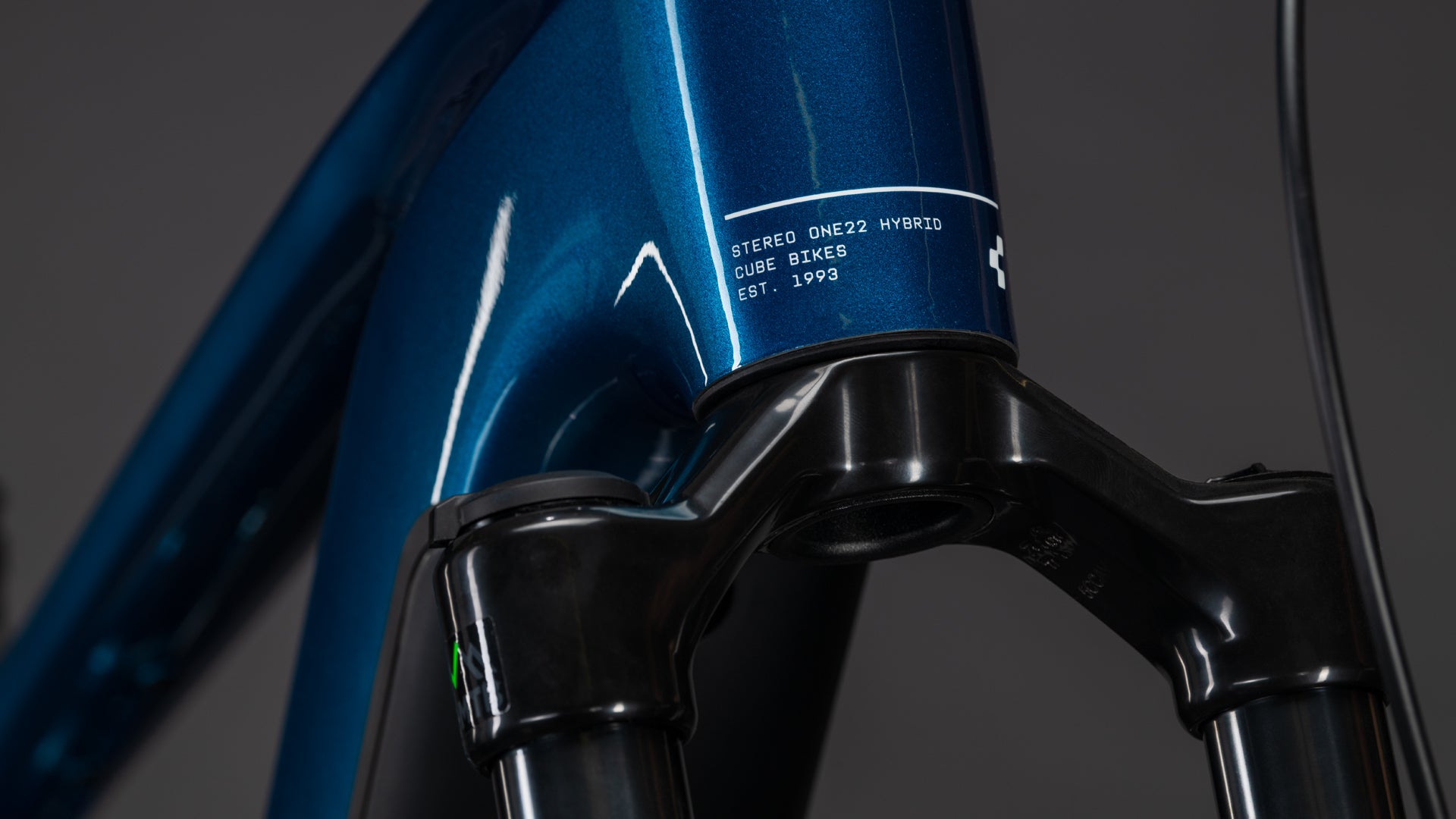 Nahaufnahme eines blauen CUBE Stereo Hybrid ONE22 Race 800 electricblue'n'white 2026 Rahmens mit Bosch CX Motor, der die vordere Federgabel und den Steuersatz vor einem dunklen Hintergrund zeigt.