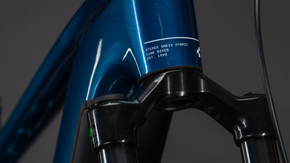 Nahaufnahme eines blauen CUBE Stereo Hybrid ONE22 Race 800 electricblue'n'white 2026 Rahmens mit Bosch CX Motor, der die vordere Federgabel und den Steuersatz vor einem dunklen Hintergrund zeigt.