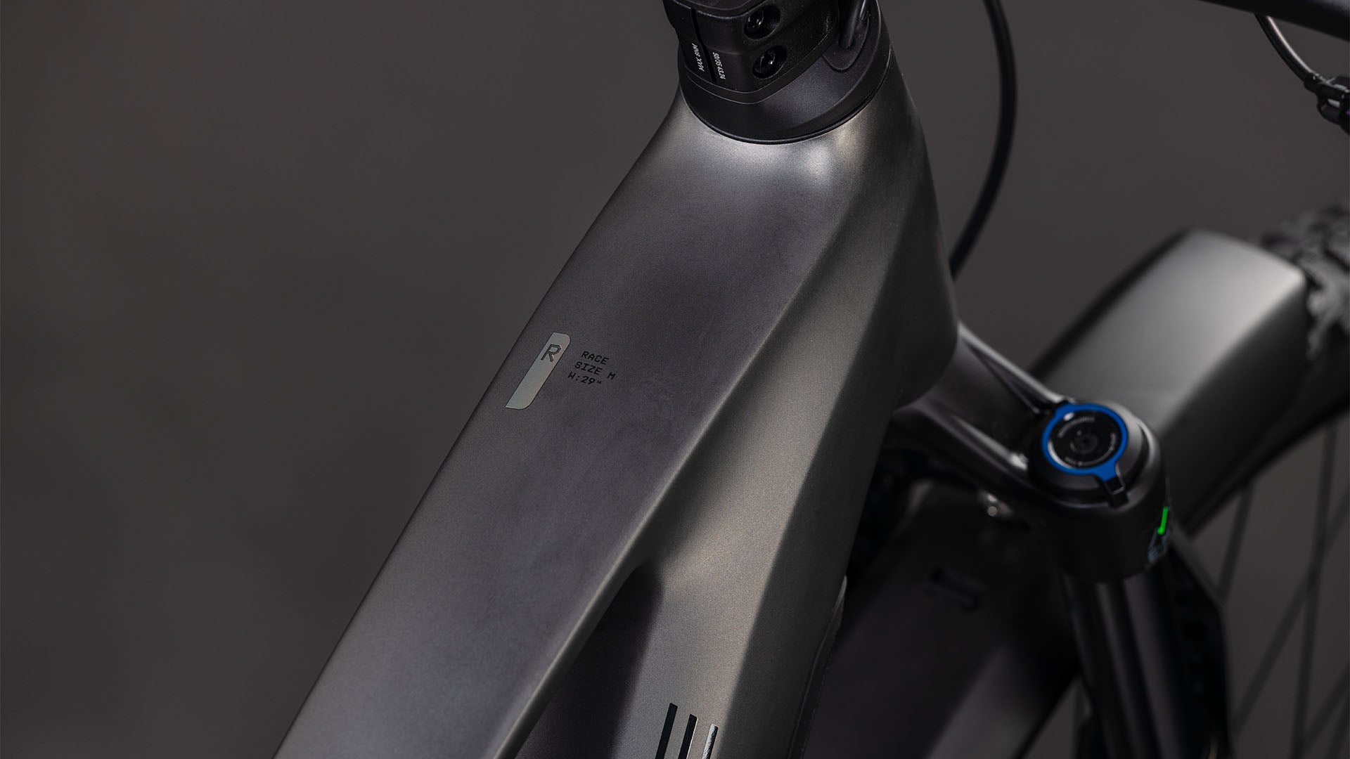 Nahaufnahme des mattschwarzen Rahmens des CUBE Stereo Hybrid ONE22 Race 800 FE slabgrey'n'chrome 2026 E-Bikes, die das minimalistische Design mit Lenker- und Gabeldetails vor einem dunklen Hintergrund hervorhebt.