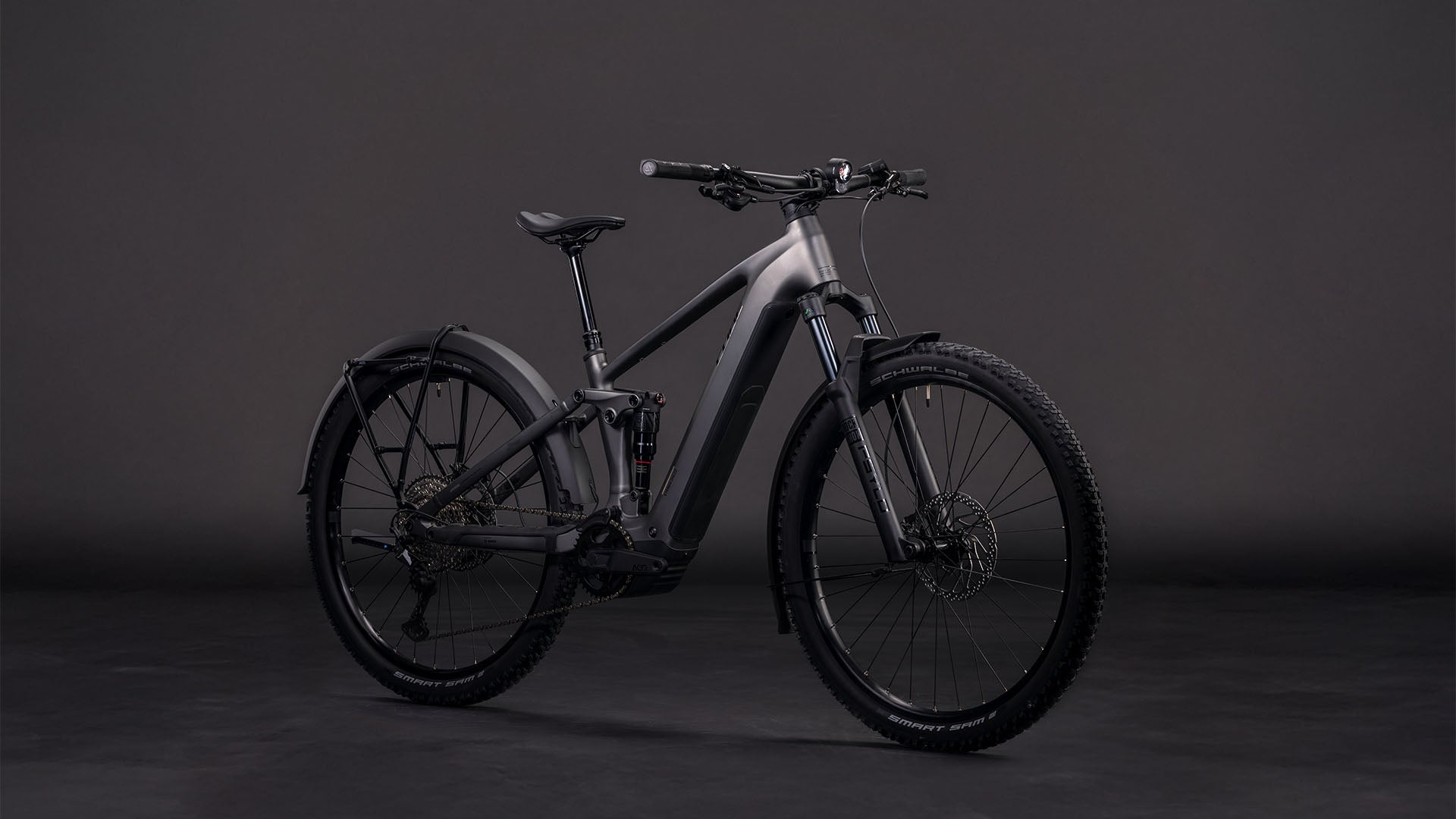 Das CUBE Stereo Hybrid ONE22 Race 800 FE slabgrey'n'chrome 2026, ein modernes E-Mountainbike mit Bosch CX-Motor, Vollfederung und dicker Bereifung, wird vor dunklem Hintergrund in Szene gesetzt.