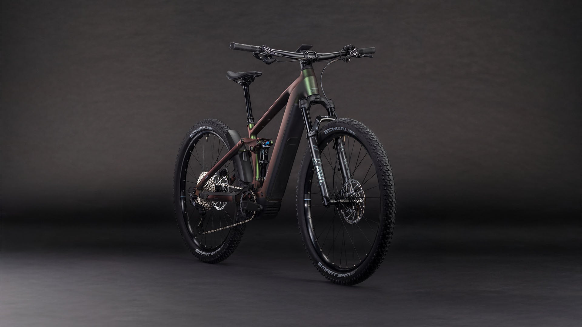 Das Cube Stereo Hybrid ONE22 SLX 800 stellar'n'green 2026 von CUBE verfügt über einen matten, dunklen Rahmen, einen Bosch CX-Antrieb, eine Shimano XT 12-Gang-Schaltung, eine Vorder- und Hinterradfederung, dicke Reifen mit Profil und Scheibenbremsen - schräg fotografiert auf einem dunklen, nahtlosen Hintergrund.