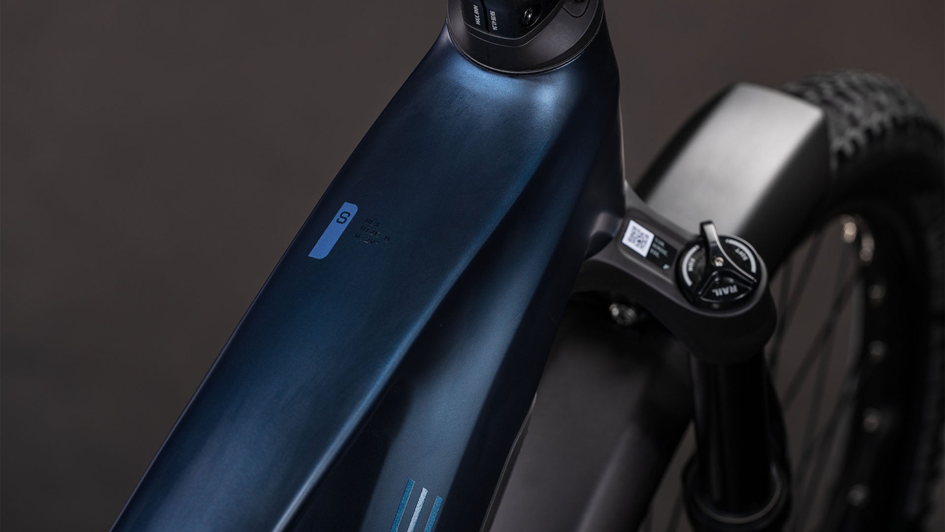 Nahaufnahme des CUBE Stereo Hybrid ONE22 SLX 800 FE indigoblue'n'blue 2026, die den schlanken dunkelblauen Rahmen, die integrierten Bedienelemente, den knorrigen Vorderreifen, die Federgabel und den leistungsstarken Bosch CX-Motor zeigt.