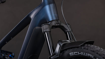 Nahaufnahme der vorderen Federgabel des CUBE Stereo Hybrid ONE22 SLX 800 FE indigoblue'n'blue 2026, des Laufrads mit robustem Schwalbe-Reifenprofil, des Schutzblechs, des Bosch CX-Motors und des schlanken Rahmens vor einem dunklen Hintergrund.