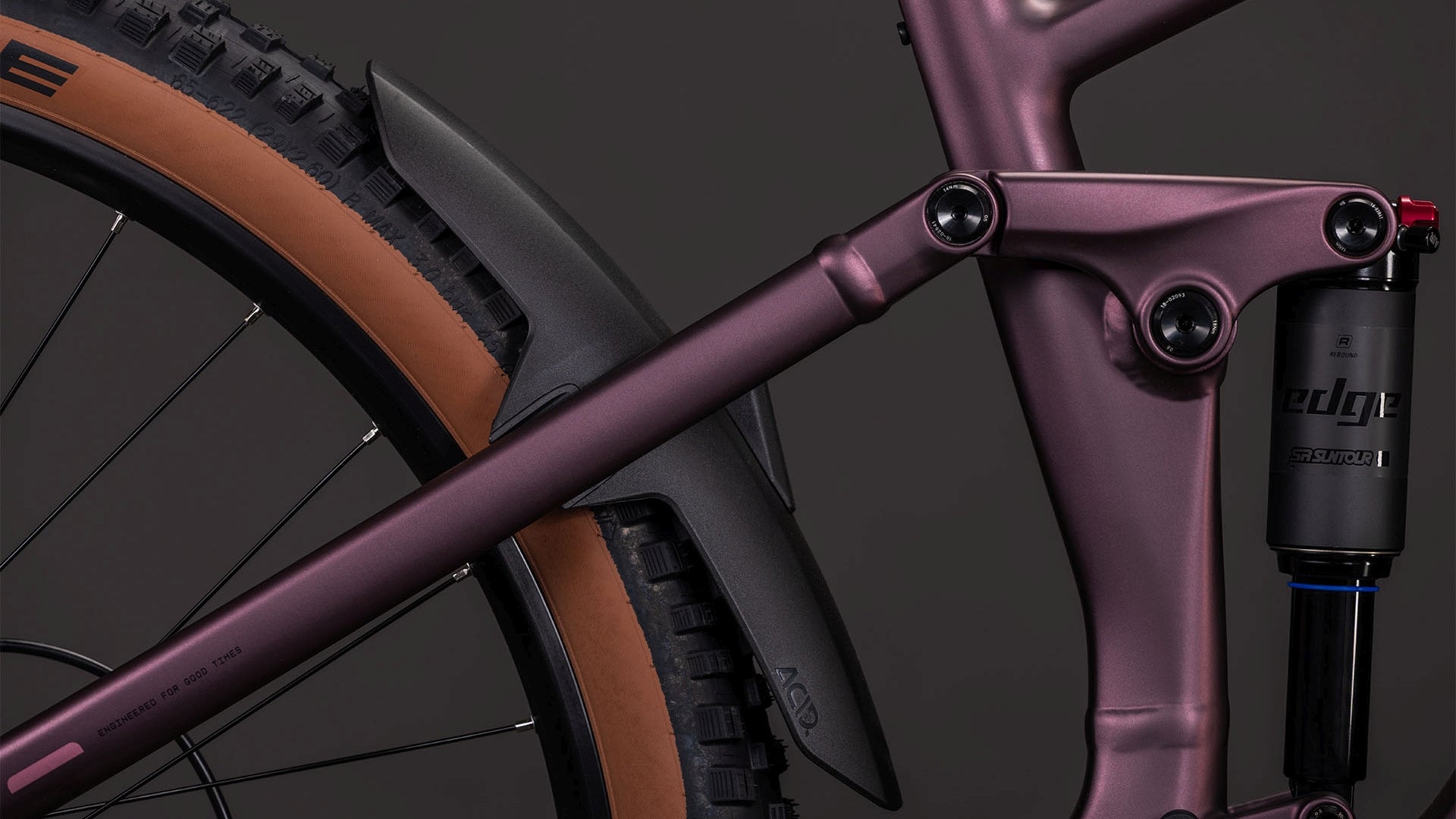 Nahaufnahme des CUBE Stereo Hybrid ONE44 Pro 800 shiftblush'n'raisin 2026 E-Mountainbike-Rahmens in mattem Lila mit Hinterradreifen, schwarzem Schutzblech, Federungssystem, brauner Seitenwand und Bosch CX-Motor vor dunklem Hintergrund.