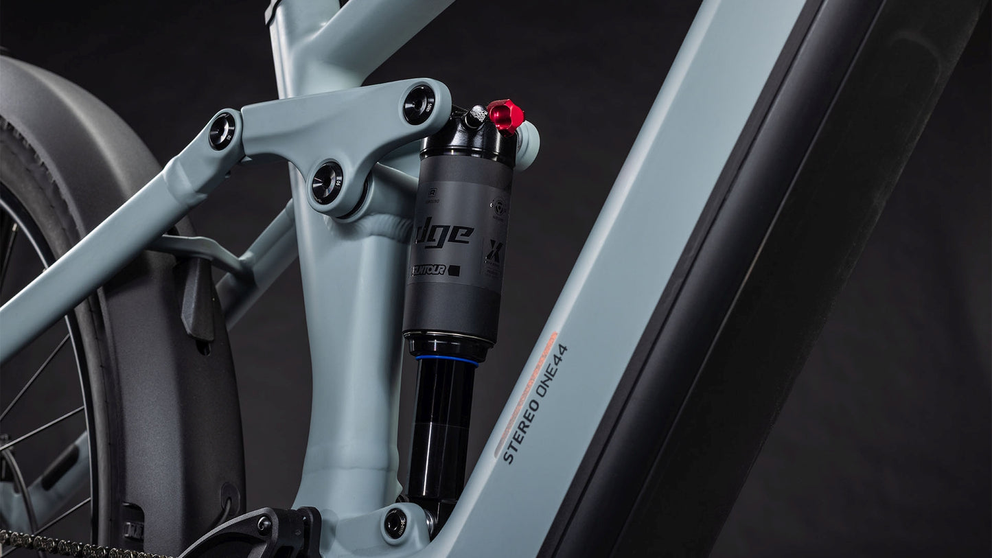 Nahaufnahme der Hinterradaufhängung und des Rahmens des CUBE Stereo Hybrid ONE44 Pro 800 FE vulcan'n'orange 2026. Zu sehen ist ein schwarzer Stoßdämpfer mit Einstellknopf; der integrierte Bosch CX-Motor sorgt für starke Leistung.