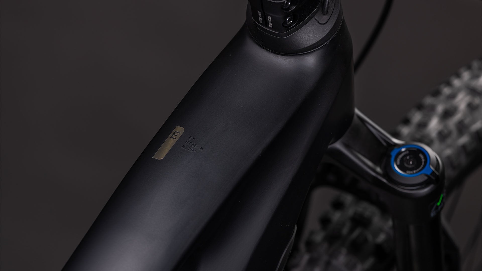 Nahaufnahme des CUBE Stereo Hybrid ONE44 EX 800 blackline 2026-Rahmens mit Schwerpunkt auf dem mattschwarzen Oberrohr, der vorderen Federgabel, dem integrierten Bosch CX-Antrieb, der Metallplakette mit Text und den robusten Reifen.