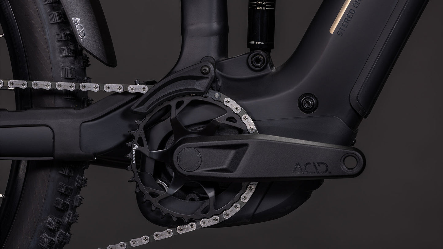Nahaufnahme der Kurbelgarnitur des CUBE Stereo Hybrid ONE44 EX 800 blackline 2026, die den ACID-Pedalarm und den Getriebemechanismus hervorhebt, wobei der Bosch CX-Antrieb deutlich vor einem dunklen Hintergrund zu sehen ist.