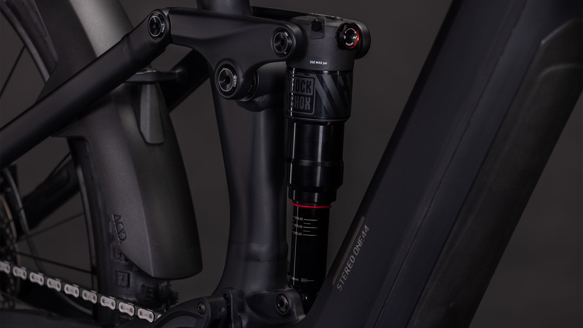Nahaufnahme des CUBE Stereo Hybrid ONE44 EX 800 blackline 2026-Rahmens mit mattschwarzem Finish, RockShox-Hinterradfederung, Bosch CX-Antrieb, "STEREO"-Schriftzug sowie sichtbarer Kette und Hinterrad.