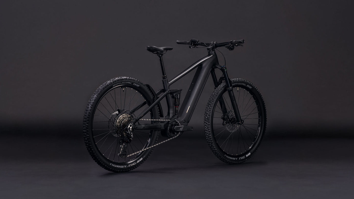 Das CUBE Stereo Hybrid ONE44 EX 800 blackline 2026 E-Bike ist schräg vor einem dunklen Hintergrund abgebildet. Die dicken Reifen und die Vollfederung unterstreichen sein modernes, mattschwarzes und robustes Design.