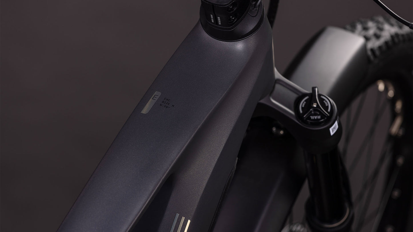 Nahaufnahme des CUBE Stereo Hybrid ONE44 EXC 800 FE irongrey'n'chrome 2026 Rahmens. Hervorzuheben sind das mattschwarze Oberrohr, die Vordergabel, der Lenker mit Federknauf und der dezent sichtbare Bosch CX Motor vor einem dunklen, unscharfen Hintergrund.