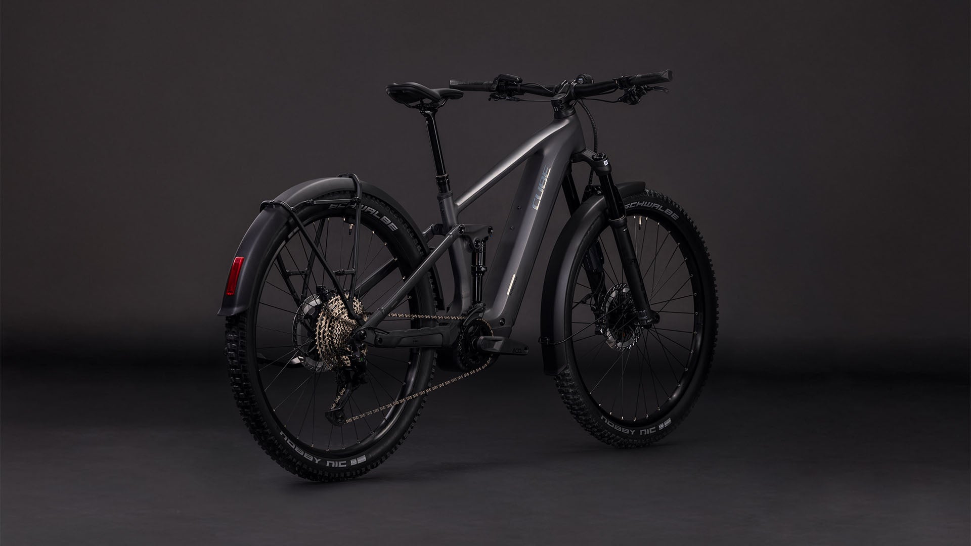 Das CUBE Stereo Hybrid ONE44 EXC 800 FE in irongrey'n'chrome (2026) ist ein E-Bike mit dicken Reifen, Scheibenbremsen, hinterem Schutzblech, sichtbarer Schaltung und einem leistungsstarken Bosch CX-Motor - dargestellt vor einem dunklen Studiohintergrund.