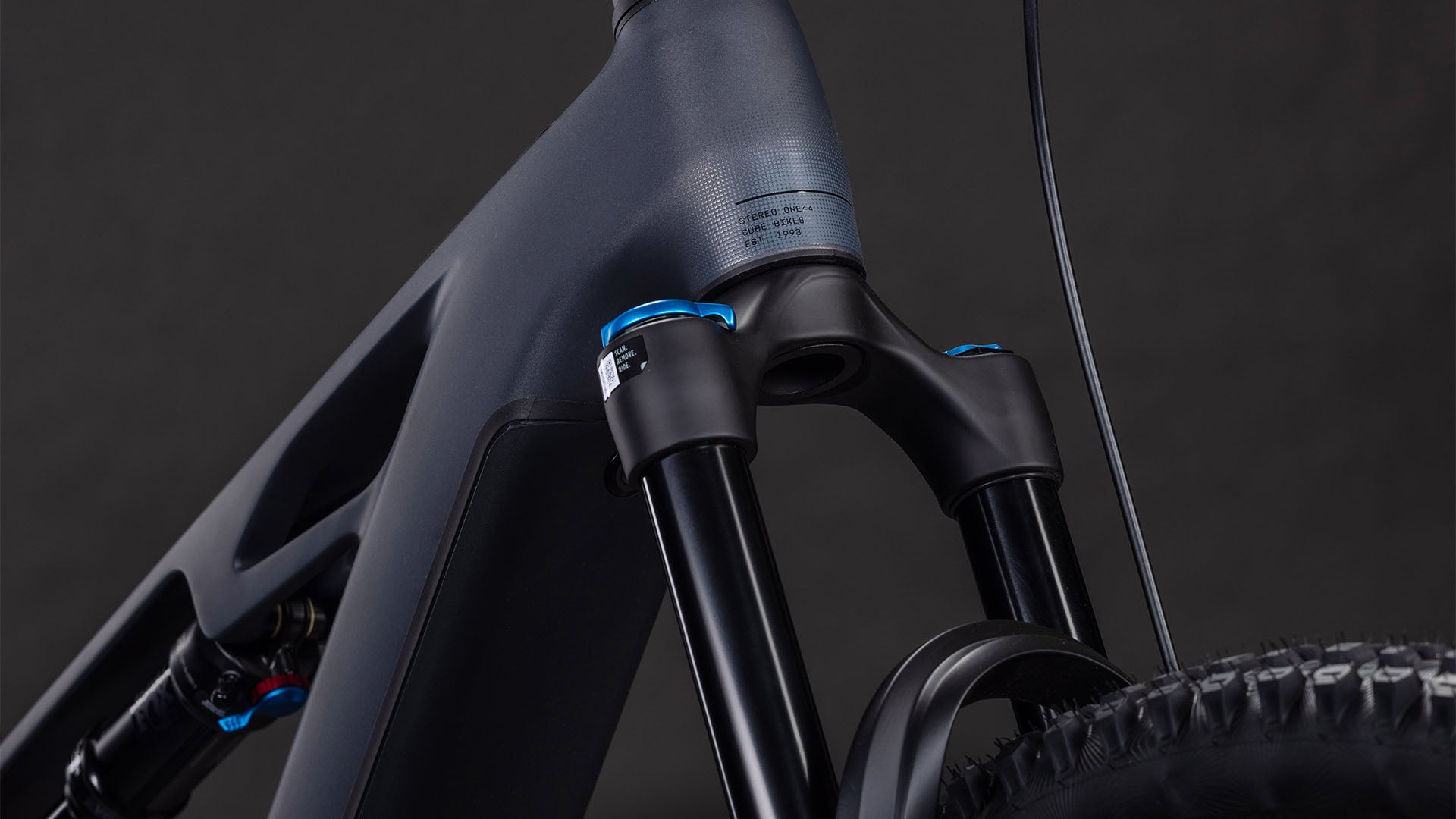 Nahaufnahme des CUBE Stereo Hybrid ONE44 HPC SLX 800 slabgrey'n'orange 2026 mit Federgabel, mattgrauem Rahmen mit orangefarbenen und blauen Akzenten und Vorderradreifen - ein Beweis für modernste E-Bike-Technik.