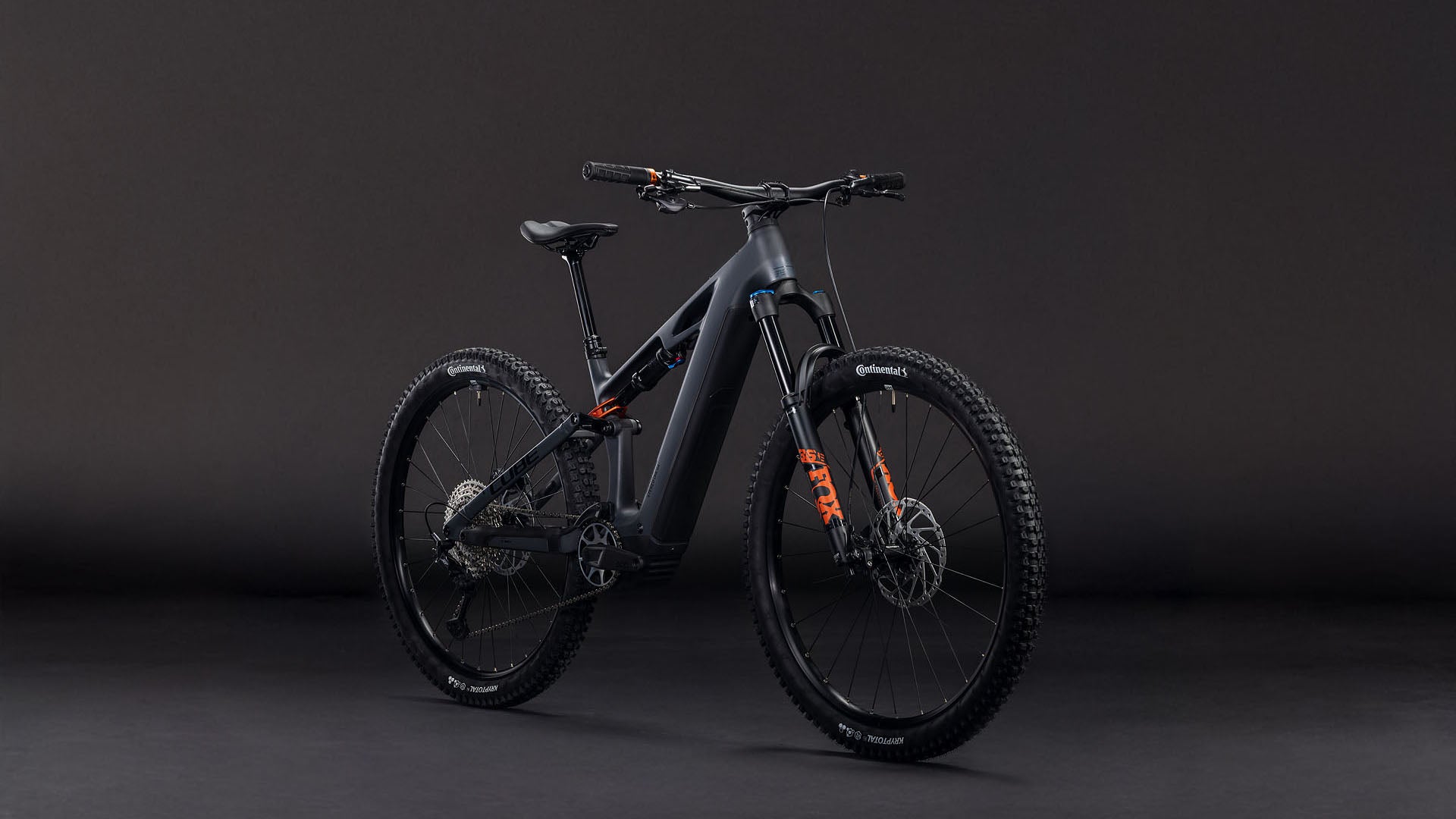 Das CUBE Stereo Hybrid ONE44 HPC SLX 800 slabgrey'n'orange 2026 Mountainbike mit Bosch CX Motor, Shimano XT Schaltung, Scheibenbremsen und orangen Akzenten steht aufrecht und schräg links vor einem dunklen Hintergrund.