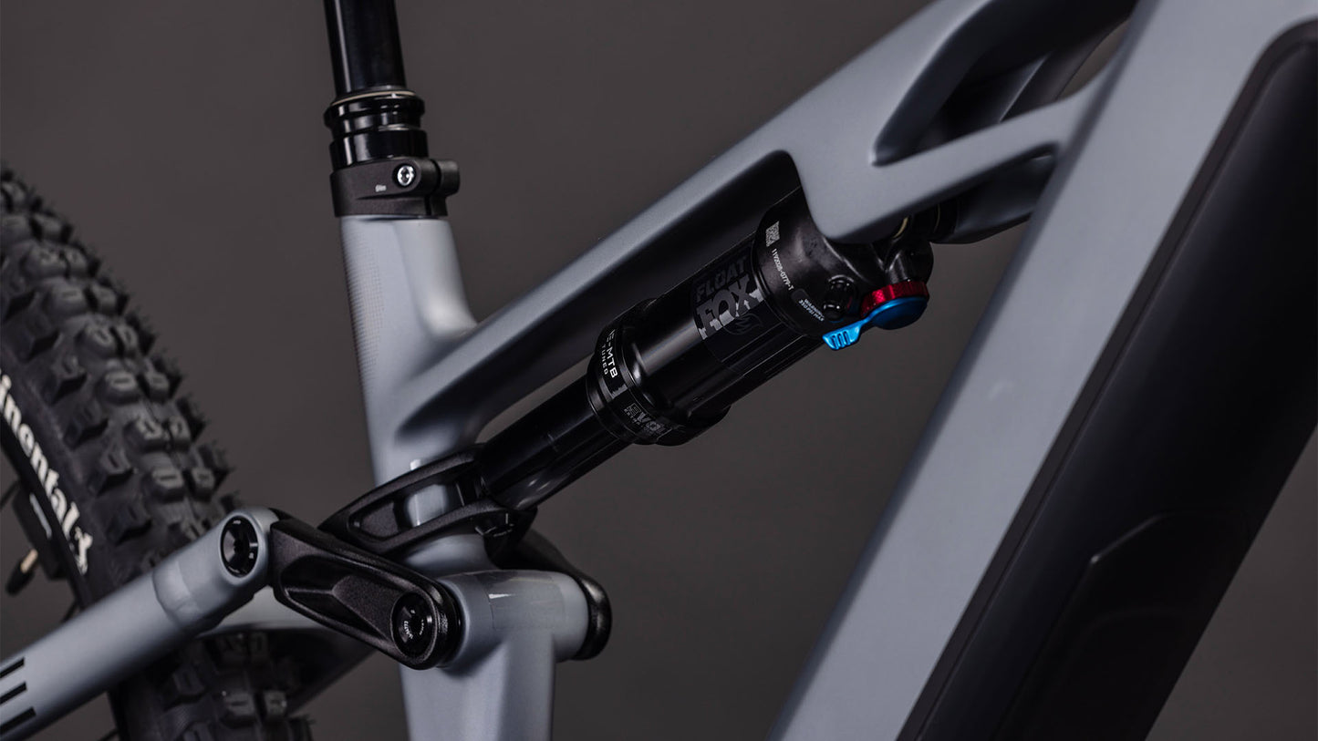 Nahaufnahme des CUBE Stereo Hybrid ONE44 HPC SLX Evo 800 (slategrey'n'black, 2026) Rahmens, die das hintere Federungssystem mit schwarzem Stoßdämpfer, detaillierter Anlenkung und leistungsstarkem Bosch CX Motor vor dunklem Hintergrund zeigt.