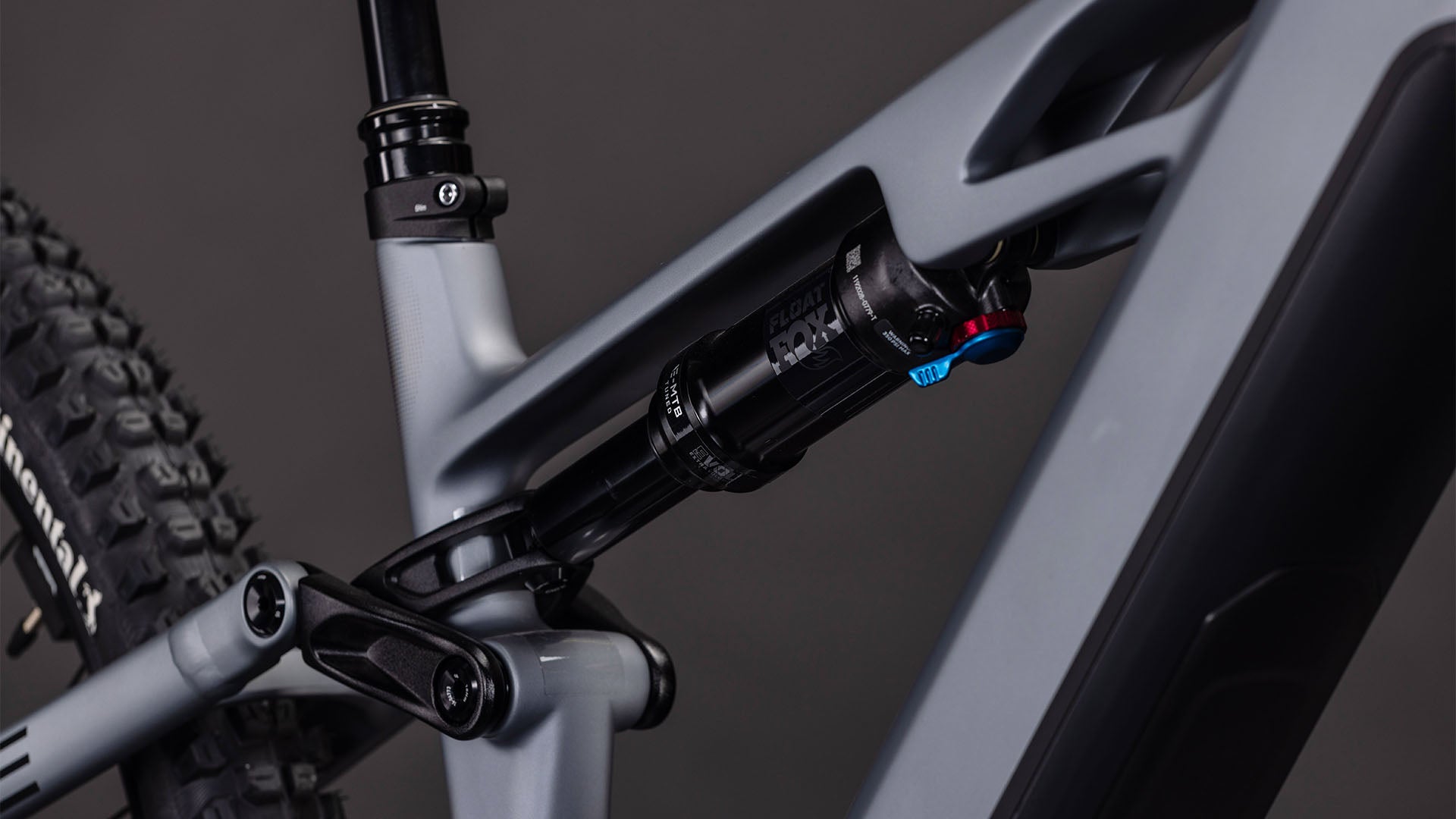 Nahaufnahme des CUBE Stereo Hybrid ONE44 HPC SLX Evo 800 (slategrey'n'black, 2026) Rahmens, die das hintere Federungssystem mit schwarzem Stoßdämpfer, detaillierter Anlenkung und leistungsstarkem Bosch CX Motor vor dunklem Hintergrund zeigt.