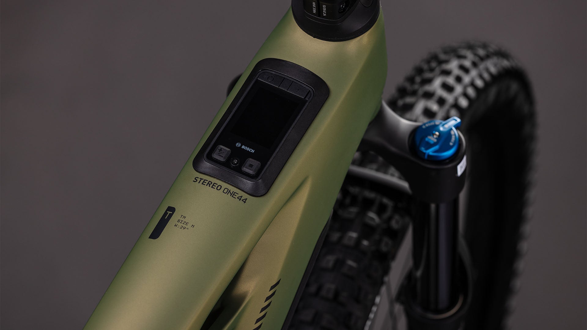 Nahaufnahme des CUBE Stereo Hybrid ONE44 HPC TM 800 reedgreen'n'matrix 2026 E-Mountainbike Rahmens mit Bosch Display und Bedienelementen. Der Schriftzug "STEREO ONE44", die Federgabel und der Noppenreifen sind ebenfalls zu sehen.
