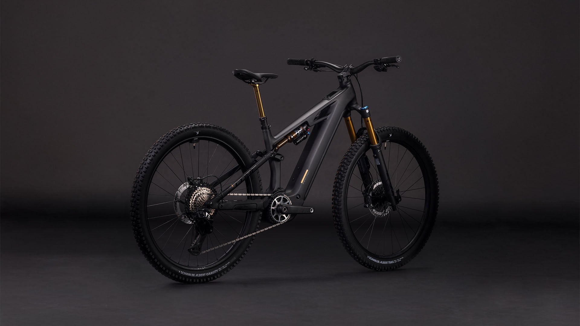 Das CUBE Stereo Hybrid ONE44 HPC AT 800 carbon'n'gold 2026 Elektro-Mountainbike besticht durch sein modernes schwarz-goldenes Design, die dicken Reifen, den Bosch CX-Motor und die auffällige goldene Federgabel, die sich auf dunklem Grund präsentiert.