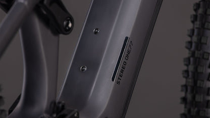 Nahaufnahme des CUBE Stereo Hybrid ONE77 HPC Race 800 in irongrey'n'black, mit dem STEREO ONE77-Logo auf dem Unterrohr, Hinterradfederung, Noppenreifen und Shimano XT 12-fach Schaltung im Hintergrund.