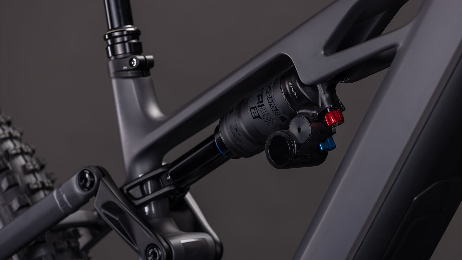 Nahaufnahme der Hinterradaufhängung des CUBE Stereo Hybrid ONE77 HPC Race 800. Hervorzuheben sind der Stoßdämpfer und das irongrey'n'black Rahmenfinish vor einem dunklen Hintergrund.