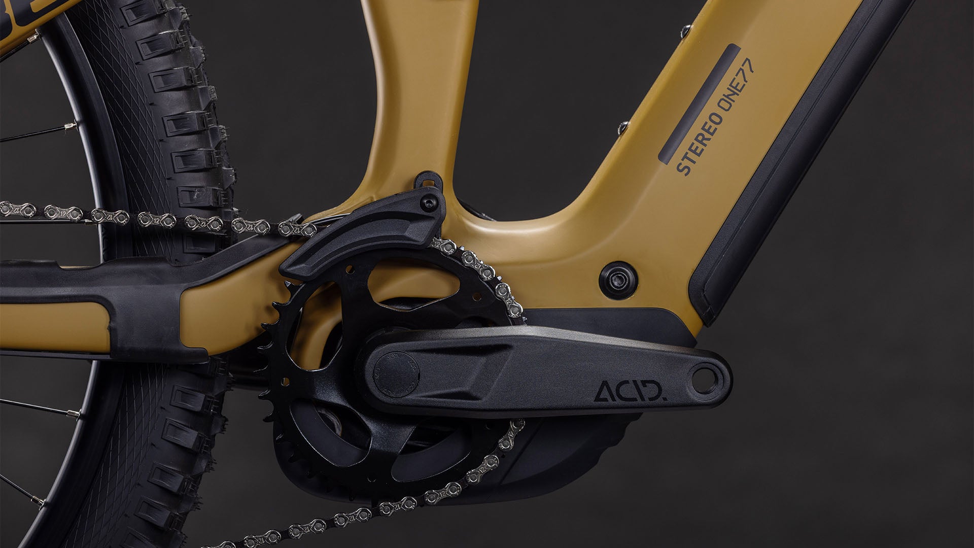 Nahaufnahme eines weidengrünen CUBE Stereo Hybrid ONE77 HPC Race 800 mit Antrieb und Kurbelgarnitur. Hervorzuheben sind die Shimano XT 12-fach Schaltung und der Hinterreifen vor einem schlichten schwarzen Hintergrund mit "ONE77" auf dem Rahmen.
