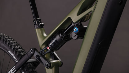 Nahaufnahme des CUBE Stereo Hybrid ONE77 HPC TM 800 reedgreen'n'matrix 2026, die den mattgrünen Rahmen, das Federbein, die schwarzen Komponenten und einen Teil des Hinterrads vor einem dunklen Hintergrund zeigt.