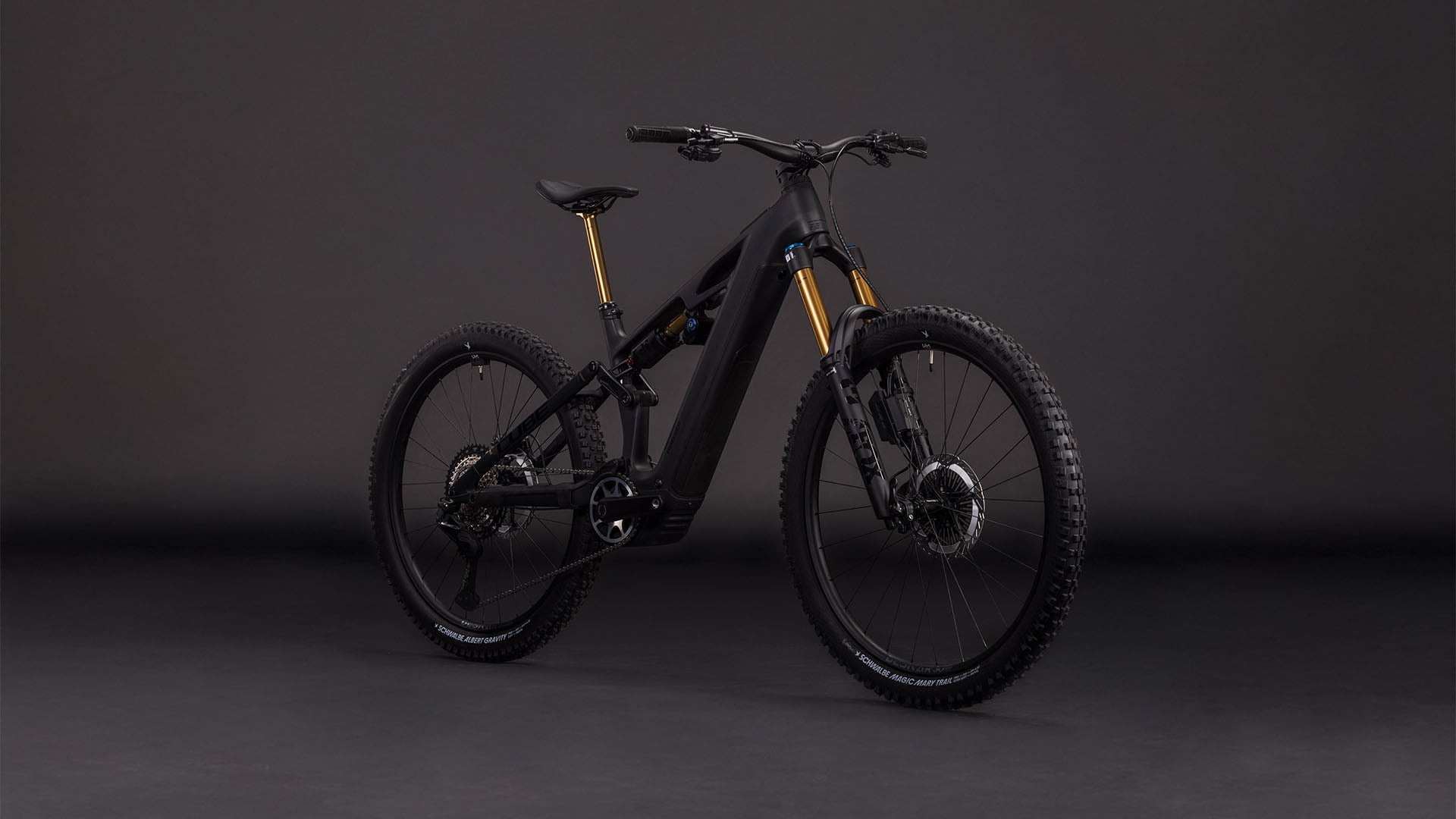 Das CUBE Stereo Hybrid ONE77 HPC AT 800 carbon'n'gold 2026 ist ein modernes schwarzes Elektro-Mountainbike mit Bosch CX-Motor, dicken Reifen, Federung vorne und hinten und goldfarbenen Gabeln, das vor einem schlichten dunklen Hintergrund gezeigt wird.