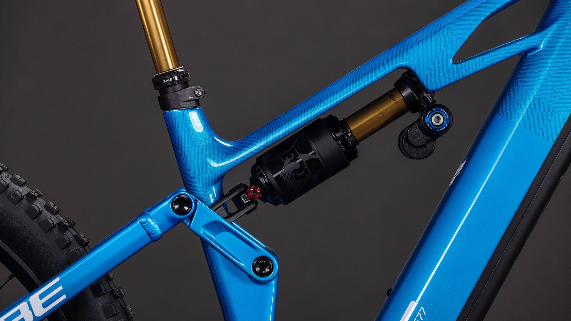 Nahaufnahme des blauen Rahmens des CUBE Stereo Hybrid ONE77 HPC AT 800 actionteam 2026 mit Hinterradfederung, fortschrittlichem Gestängesystem und Bosch CX-Motor vor einem dunklen Hintergrund.