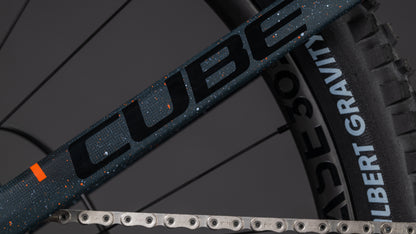 Nahaufnahme des CUBE Stereo Hybrid ONE77 HPC SLT 800 galaxy'n'orange 2026 Rahmens, der Big-Mountain-Performance mit SCHWALBE G-ONE RACE 50 Reifen und Kette zeigt - gebaut für kraftvolle Fahrten.