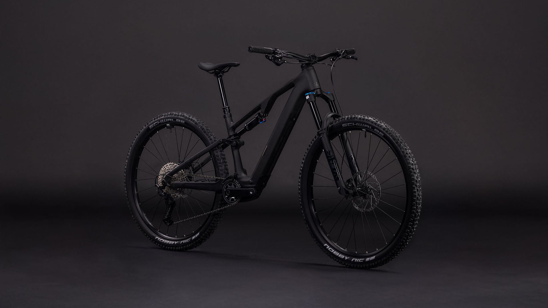 Das CUBE AMS Hybrid ONE44 C:62 Pro 400X blackline 2026 Mountainbike verfügt über einen robusten Carbonrahmen, dicke Reifen und einen Bosch SX Antrieb, der vor einem dunklen Hintergrund präsentiert wird, um das elegante schwarze Design und die fortschrittlichen Komponenten zu betonen.