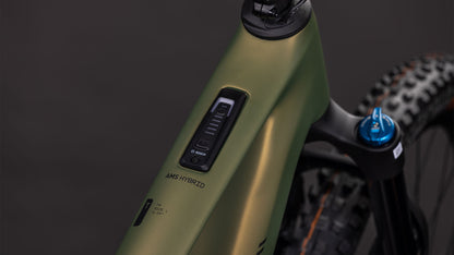 Nahaufnahme eines CUBE AMS Hybrid ONE44 C:68X TM 400X reedgreen'n'matrix 2026 Rahmens mit dem Bosch SX Motor Bedienfeld mit der Aufschrift AMS HYBRID und einem Teil der Fox Fahrwerk Federgabel mit einem blauen Einstellknopf.