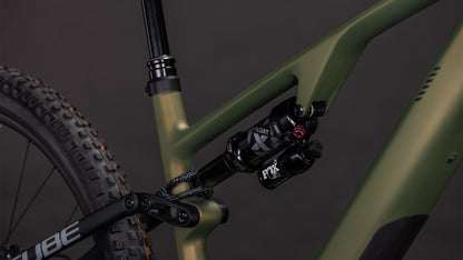 Nahaufnahme der Hinterradaufhängung an einem CUBE Cube AMS Hybrid ONE44 C:68X TM 400X reedgreen'n'matrix 2026, wobei der schwarze Fox-Dämpfer und ein Teil des Rahmens vor einem dunklen Hintergrund hervorgehoben werden.