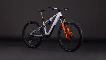 Das CUBE AMS Hybrid ONE44 C:68X SUPER TM 400X foggrey'n'fibre 2026 ist ein modernes, vollgefedertes All-Mountain-Bike mit einem nebelgrauen Carbonrahmen, schwarzen Laufrädern und einer orangefarbenen Vorderradgabel, das vor einem dunklen Studiohintergrund gezeigt wird.