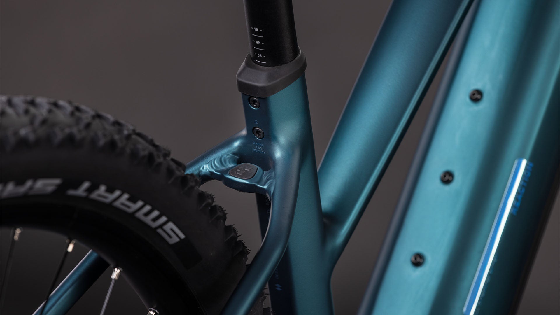 Nahaufnahme des CUBE Reaction Hybrid ONE 800 in royalgreen'n'prism Trapeze 2026, die das Sitzrohr, den Hinterreifen mit SMART SAM-Branding, einen Teil des Unterrohrs und ein leistungsstarkes Bosch-Motorsystem vor einem unscharfen Hintergrund zeigt.