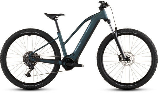 Das CUBE Reaction Hybrid ONE 800 royalgreen'n'prism Trapeze 2026 ist ein modernes E-Bike mit Bosch-Motor, Vorderrad-Federgabel, großen Stollenreifen und einem 800-Wh-Akku mit Mittelantrieb, hier von der Seite vor weißem Hintergrund.