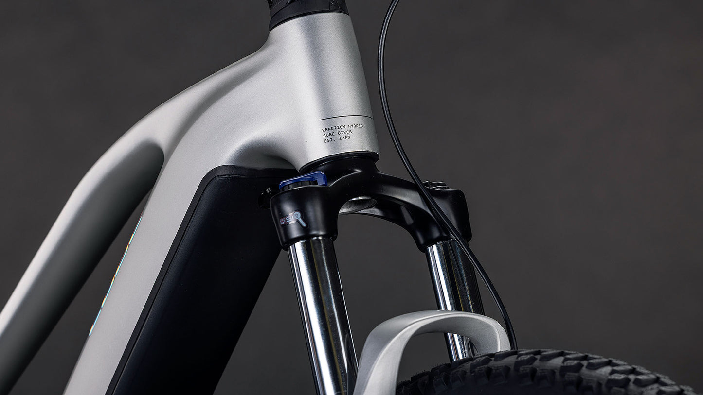 Nahaufnahme der Vorderradaufhängung, der Metallgabel und des Bosch-Motors des CUBE Reaction Hybrid ONE 800 Trapeze 2026, die vor einem dunklen Hintergrund hochwertige Leistungs- und Designdetails zeigen.