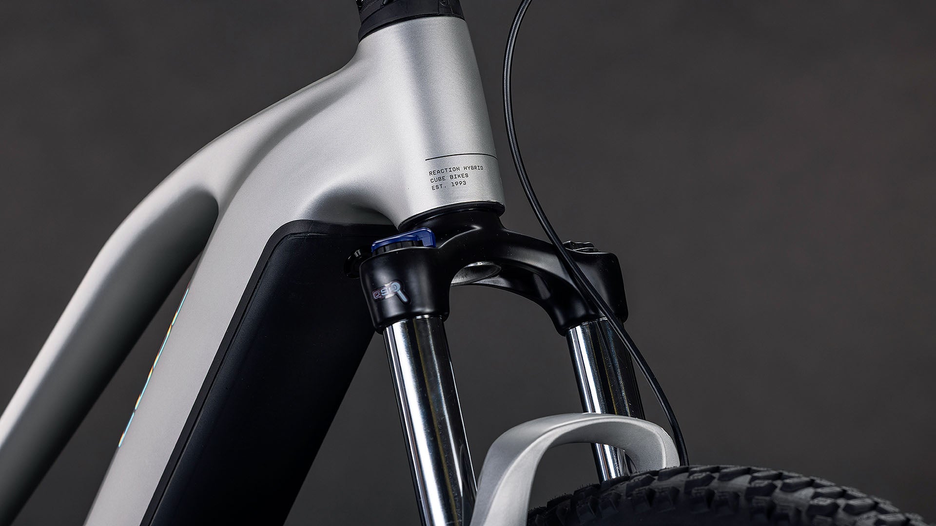 Nahaufnahme der Vorderradaufhängung, der Metallgabel und des Bosch-Motors des CUBE Reaction Hybrid ONE 800 Trapeze 2026, die vor einem dunklen Hintergrund hochwertige Leistungs- und Designdetails zeigen.