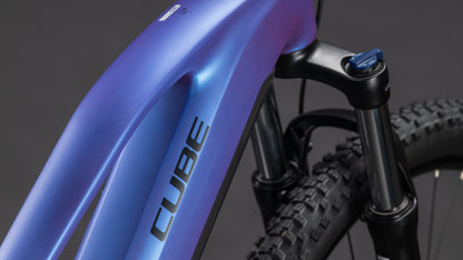 Nahaufnahme der Frontpartie des CUBE Reaction Hybrid ONE 800 blueiris'n'reflect Trapeze 2026 E-Bike, die den Rahmen, den Bosch-Motor und die Federgabel vor einem dunklen Hintergrund zeigt.