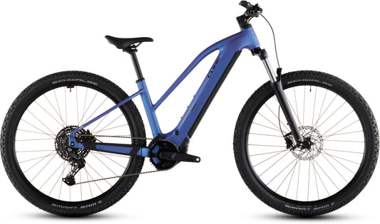 Das CUBE Reaction Hybrid ONE 800 blueiris'n'reflect Trapeze 2026 E-Bike verfügt über einen Bosch-Motor, ein abfallendes Oberrohr, eine Vorderradaufhängung, Stollenreifen und einen integrierten 800-Wh-Akku am Unterrohr, hier seitlich vor weißem Hintergrund.