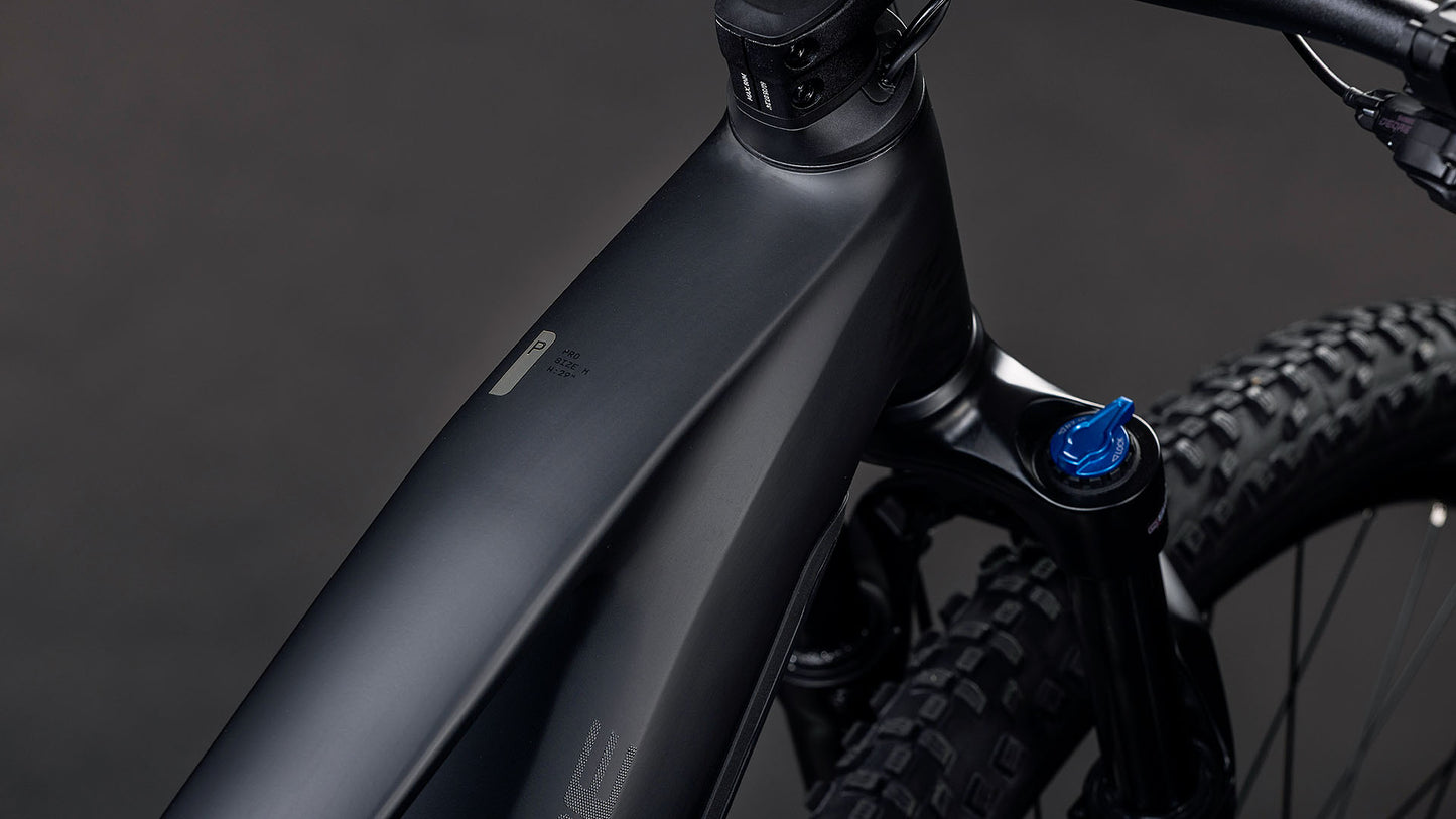 Nahaufnahme des CUBE Reaction Hybrid Pro 800 blackline 2026 E-Mountainbike-Rahmens mit mattschwarzem Finish, auffälliger Bosch CX Antrieb-Integration, sichtbarer Vorderradfederung, detailliertem Reifenprofil und blauem Einstellknopf in der Nähe des Lenkers.