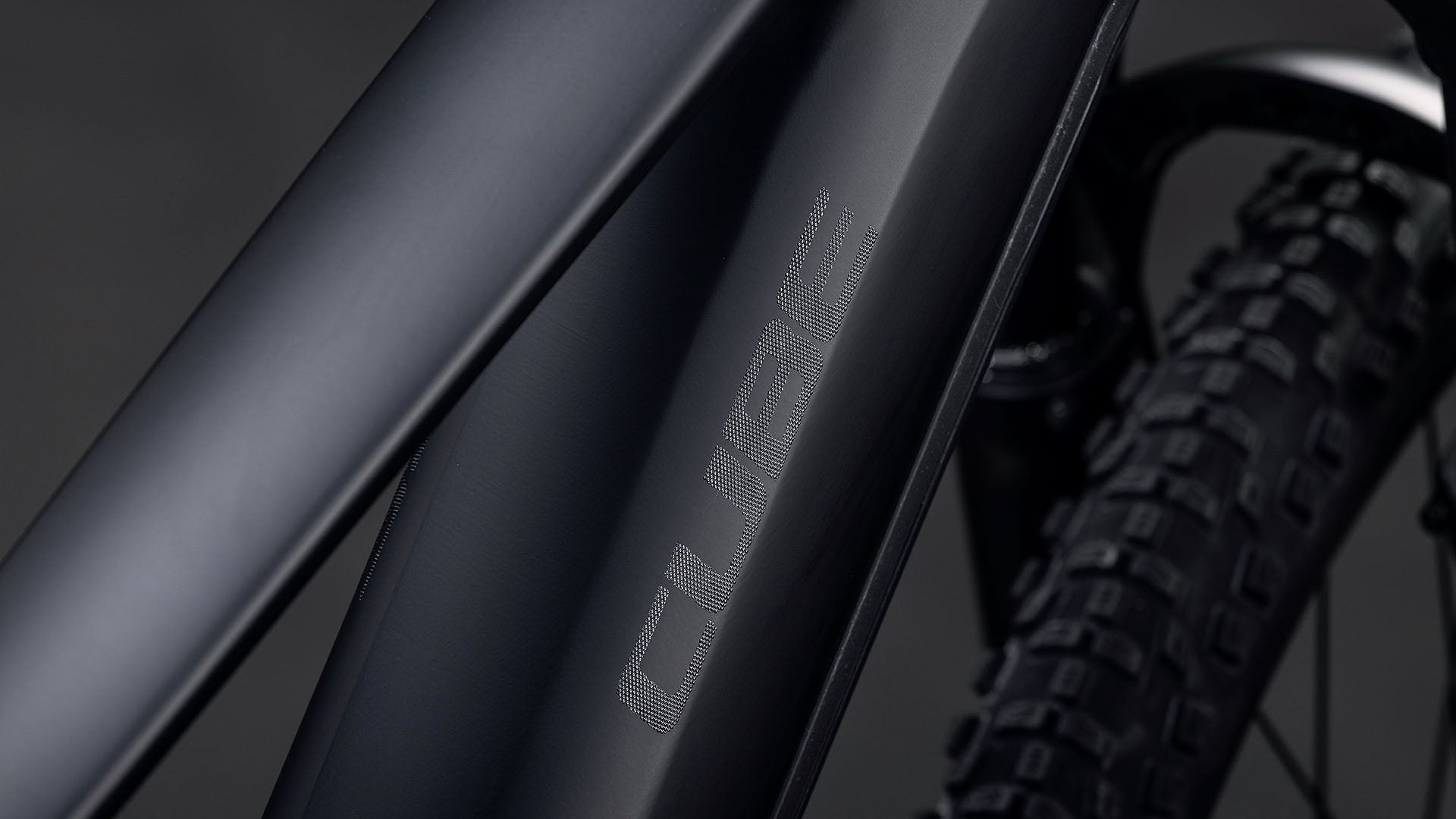 Nahaufnahme des Cube Reaction Hybrid Pro 800 blackline 2026 Rahmens in mattschwarz von CUBE, mit sichtbarem strukturierten Reifen und angedeutetem leistungsstarken Bosch CX Antrieb plus 800 Wh Akku im Hintergrund.