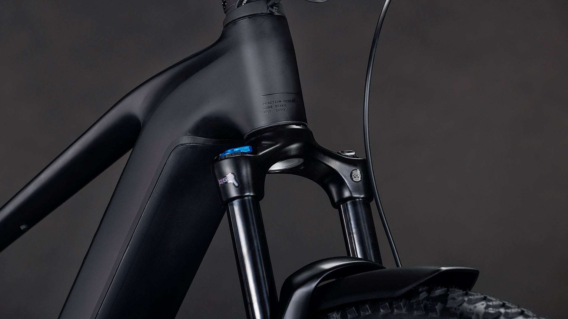 Nahaufnahme des mattschwarzen E-Bike-Rahmens CUBE Reaction Hybrid Pro 800 FE blackline 2026 mit Federgabel, Teilbereifung und Bremszug vor dunklem Hintergrund.