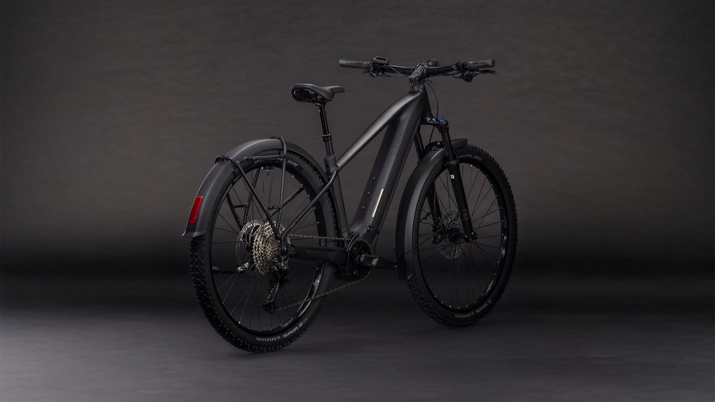 Das CUBE Reaction Hybrid Pro 800 FE blackline 2026 E-Mountainbike verfügt über dicke Reifen, Scheibenbremsen, einen eingebauten Akku, Schutzbleche vorne und hinten, ein sportlich-modernes Design und einen leistungsstarken Bosch CX-Motor - und das alles vor einem dunklen Hintergrund.