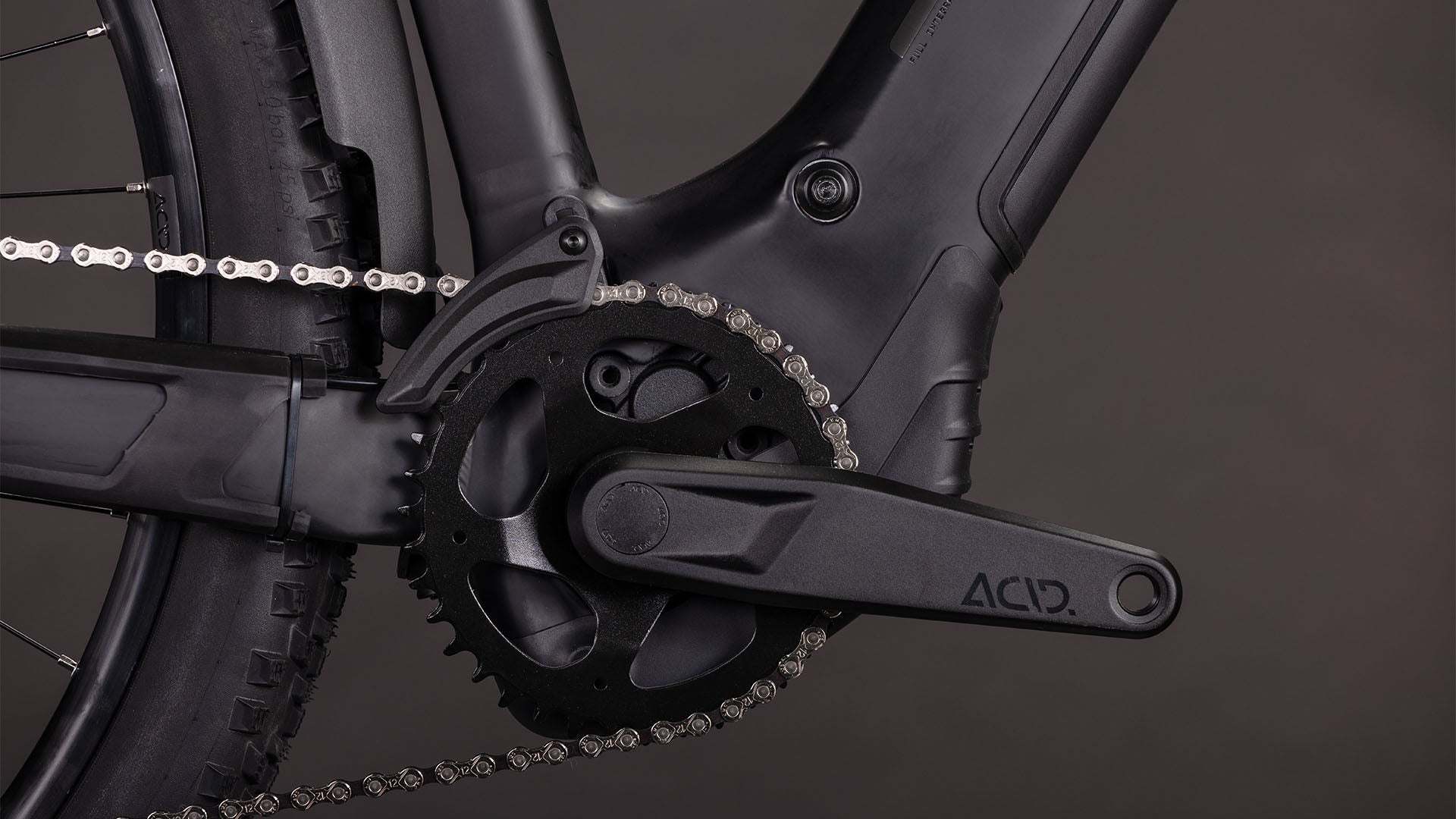 Nahaufnahme der CUBE Reaction Hybrid Pro 800 FE blackline Trapeze 2026 Kurbelgarnitur, Kettenblatt und Kette vor einem dunklen Hintergrund, mit ACID-gekennzeichnetem Kurbelarm - entwickelt für E-Bikes mit präziser Bosch CX Motorleistung.