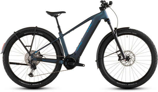 Das CUBE Reaction Hybrid Pro 800 FE nebular'n'dazzle 2026 ist ein blau-schwarzes E-Mountainbike mit breiten Reifen, Federgabel, Scheibenbremsen, Bosch CX Motor, Shimano XT 12-fach Schaltung, Schaltwerk und Schutzblechen im Seitenprofil auf weiß.