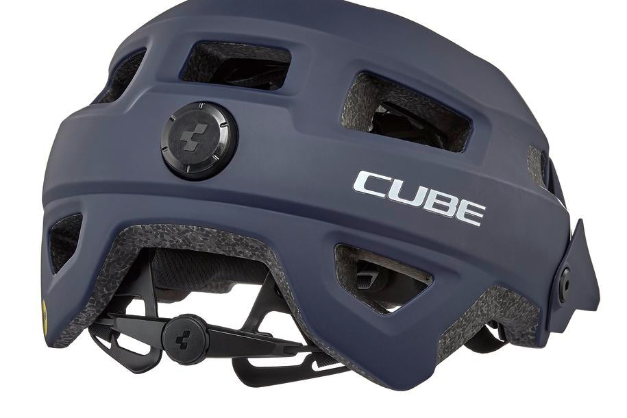 Der dunkelblaue Cube Helm FRISK / MTB Trail Helm mit mehreren Belüftungsöffnungen, MIPS-Technologie und einem verstellbaren hinteren Einstellrad mit dem Cube Natural Fit System ist von hinten vor einem weißen Hintergrund abgebildet.
