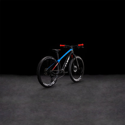 Das CUBE Elite 240 C:62 Pro carbon'n'blue'n'red 2024, ein CUBE Race-Mountainbike mit Vollcarbonrahmen in Blau und Schwarz, rotem Lenker und dicken Reifen, steht auf einer dunklen Fläche vor schwarzem Hintergrund.