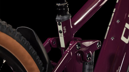 Nahaufnahme des kastanienbraunen Rahmens des CUBE Stereo Hybrid ONE22 Pro 800 amarone'n'grey 2025. Hervorzuheben sind der HPA-gekennzeichnete Federungsdrehpunkt und der Einstellhebel in der Nähe des hellbraunen Hinterreifens. Die Magura MT Thirty-Scheibenbremsen versprechen präzises Bremsen vor einem schwarzen Hintergrund.
