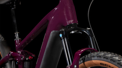 Nahaufnahme eines CUBE Stereo Hybrid ONE22 Pro 800 amarone'n'grey 2025 dark purple Rahmens, der die vordere Federgabel, den Reifen und die Kabel hervorhebt. Mit einem Shimano Cues 10-Gang-Antrieb vor einem schlichten schwarzen Hintergrund.