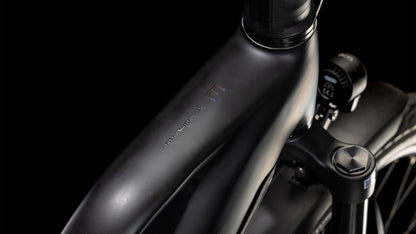 Der elegante CUBE Kathmandu Hybrid EXC 800 black'n'prism Trapeze 2025 Rahmen mit minimalistischem Branding, Bosch CX Motor, Shimano XT Schaltung und einer Digitalanzeige am Lenker vor schwarzem Hintergrund.